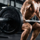 A professional male athlete lifting heavy weight during a barbell squat in a modern gym